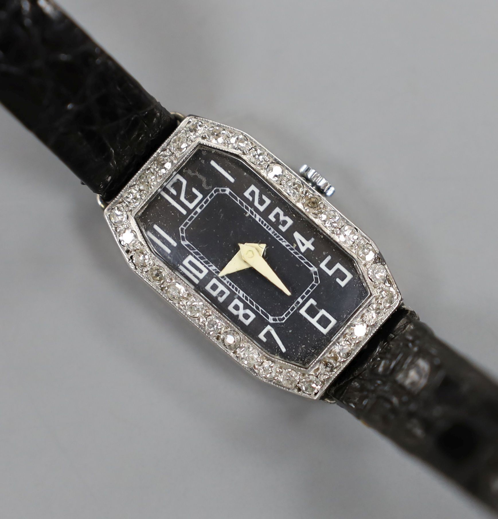 A lady's white metal (stamped platinum) and diamond set cocktail watch, on a leather strap, cased diameter 18mm, gross weight 15.8 grams.